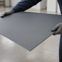 Grey PVC sheet held by gloved hands in a workshop, showing the flat surface and edge