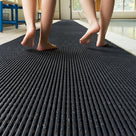 Low view along charcoal grey ribbed barefoot matting in a pool hall, wet bare feet walking away along the run