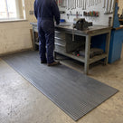 Dark grey 3mm ribbed PVC matting in front of a workshop bench with vice, technician in overalls standing on it