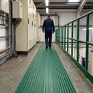 Green ribbed PVC matting walkway on a chequer-plate mezzanine beside electrical control cabinets