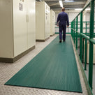 Green 3mm ribbed PVC matting walkway on a chequer-plate mezzanine beside electrical control cabinets