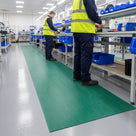 Green 3mm ribbed PVC matting run along an electronics assembly line, operatives in hi-viz standing on it
