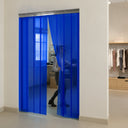 Blue transparent strip curtain between a clothing shop floor and a stockroom, staff member parting it