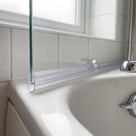 Clear seal running along the bottom edge of a bath screen, bubble sitting on the white bath rim