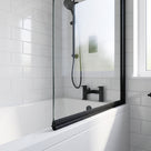 Black seal along the bottom edge of a bath screen, white metro tiles and a black bath filler behind