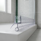 Clear seal with a round bubble tube on the bottom edge of a glass bath screen, water on the bath rim