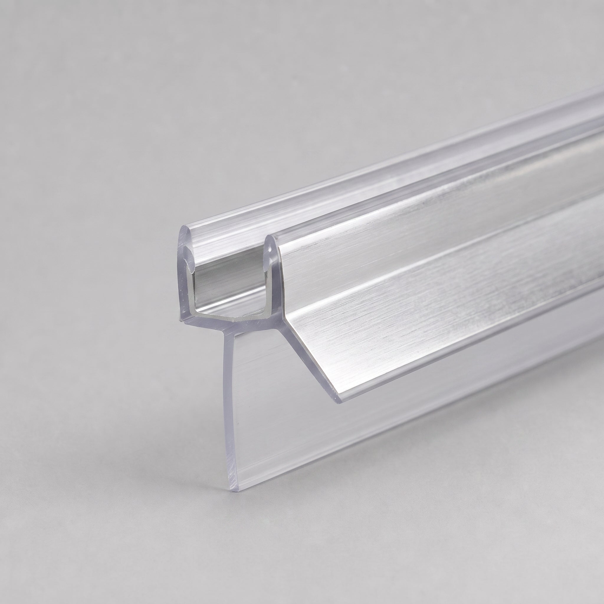 Studio shot of the chrome shower screen seal profile - clear PVC U-channel with brushed chrome strip on the angled deflector