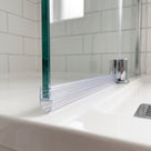 Clear bubble seal along a glass screen bottom edge on a white bath, metro tiles behind