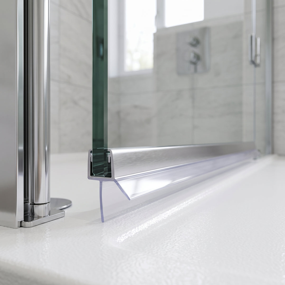 Chrome shower seal capping the bottom edge of 8-10mm glass, clear 20mm blade closing the gap to the tray
