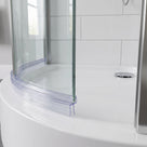 Clear seal following the curved base of a quadrant shower screen on a white bath, chrome waste behind