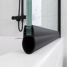 Black bulb seal on the bottom edge of a glass door, resting on a white bath with black fittings