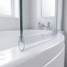 Clear pre-curved seal following the curve of a glass bath screen onto a white bath, chrome taps and window behind