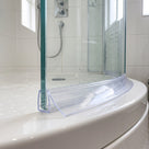 Clear curved seal along the foot of a curved bath screen, wide blade lying on the white bath rim