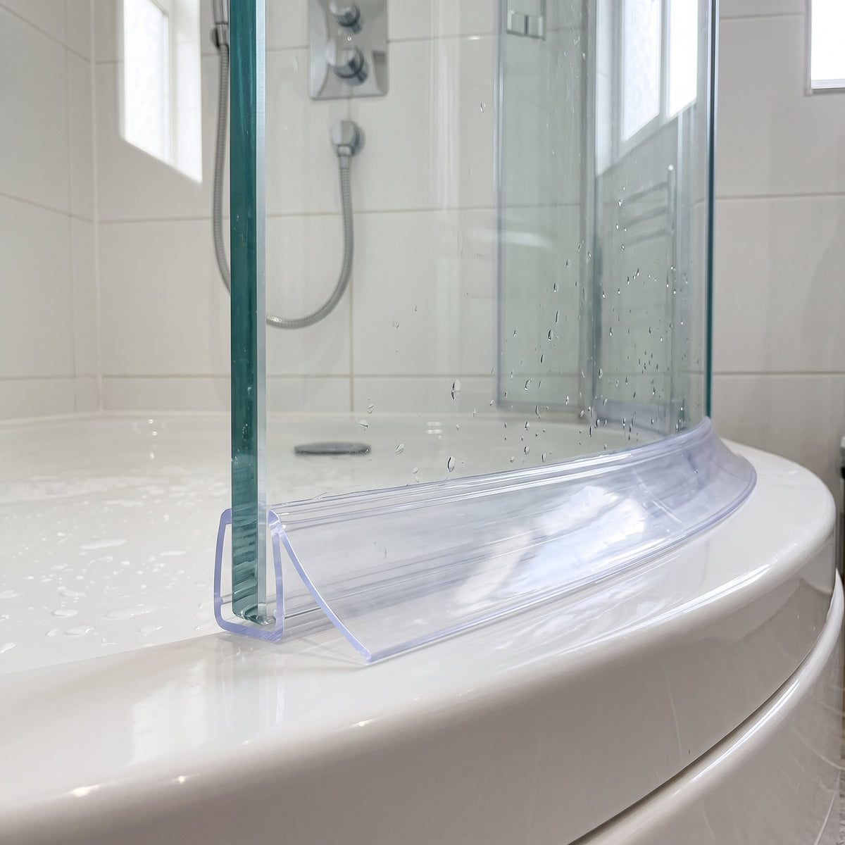 Clear curved seal along the foot of a curved bath screen, wide blade lying on the white bath rim