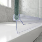Clear seal on a green-edged glass screen, angled fin and long blade resting on a white bath rim