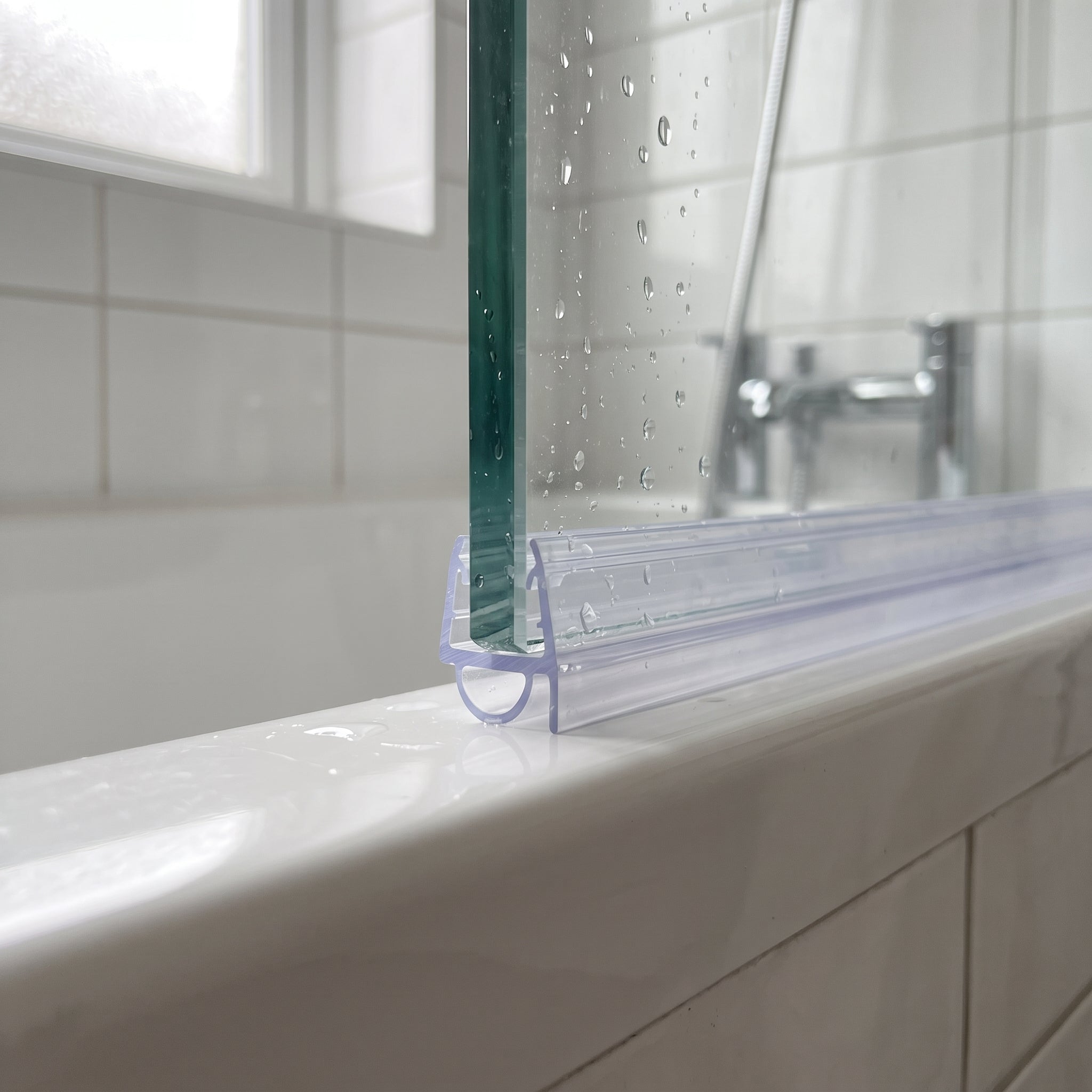 Clear SEAL053 on a bath screen bottom edge - soft bubble compressing to close a 1-3mm gap to the bath rim