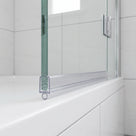 Clear seal with a small round bubble on the bottom edge of a glass bath screen above a white bath rim