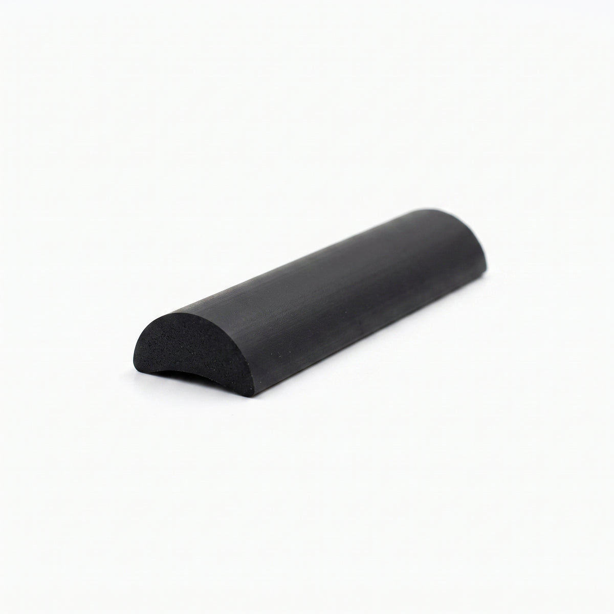 Cut length of solid black half-round threshold seal on a plain off-white studio background