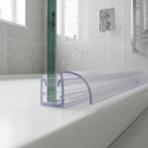 Clear seal on the bottom edge of a bath screen, curved arched fin resting on the white bath rim