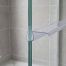 Clear seal on the upright edge of a glass shower panel, flat fin reaching across to the wall