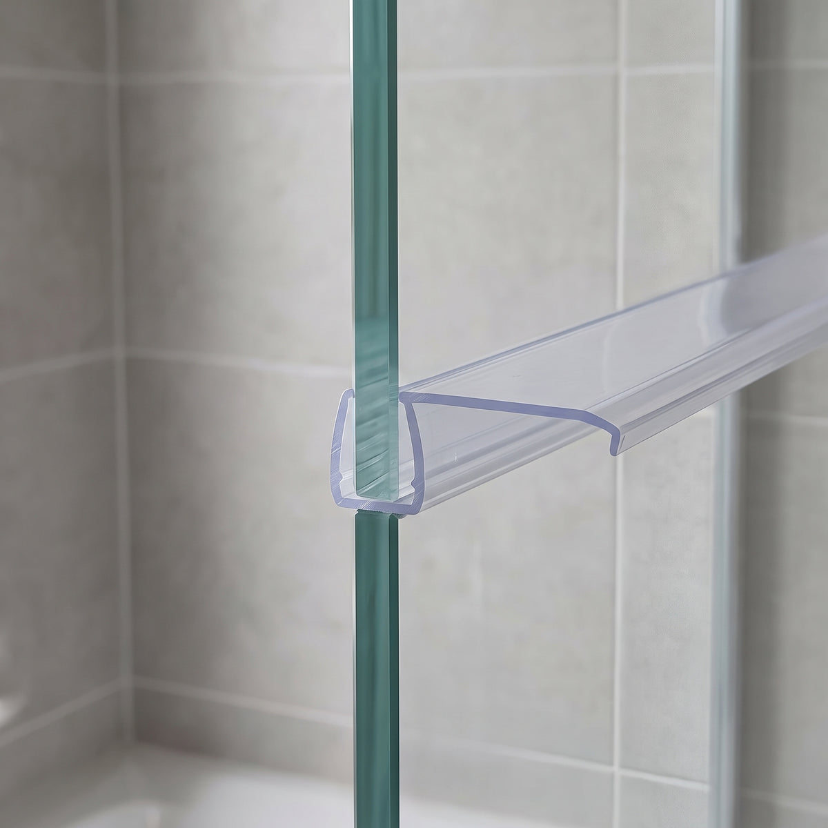 Clear seal on the upright edge of a glass shower panel, flat fin reaching across to the wall