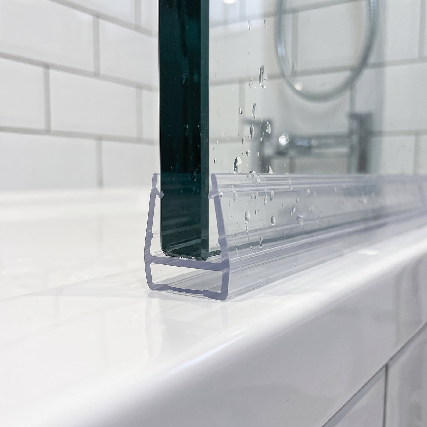 Clear SEAL085 carrier on a 10mm glass door bottom edge - zero-gap channel with empty T-slot track