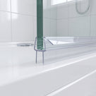 Clear seal at the foot of a glass shower screen on a white tray, white tiled bathroom behind