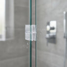 Clear join seal clipped over the vertical edge where two glass shower panels butt together, grey tiles behind