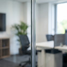 Clear I-join seal bonding two 12mm glass partition panels in line - the joint reads as a neat thin vertical line