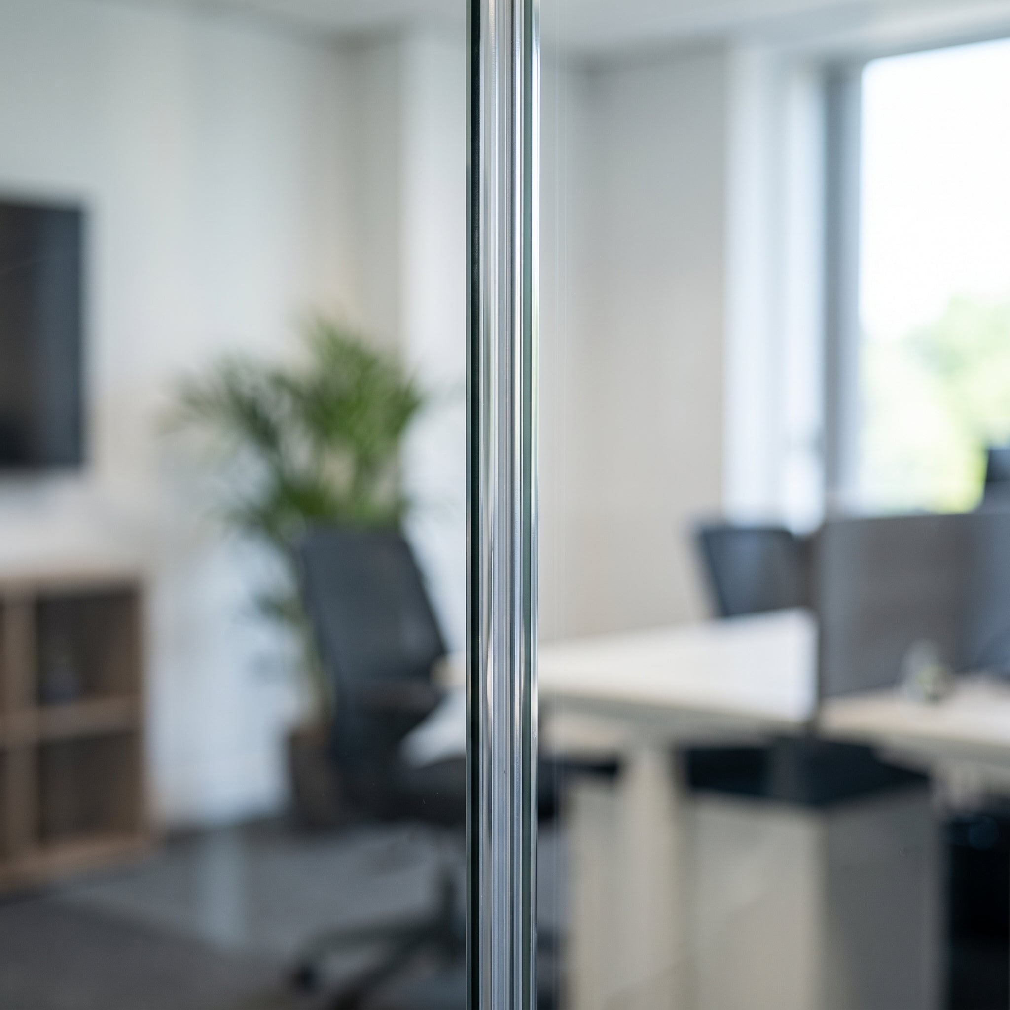 Clear I-join seal bonding two 12mm glass partition panels in line - the joint reads as a neat thin vertical line