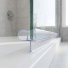 Clear seal with a rounded bubble edge fitted along the base of a glass bath screen, wet glass