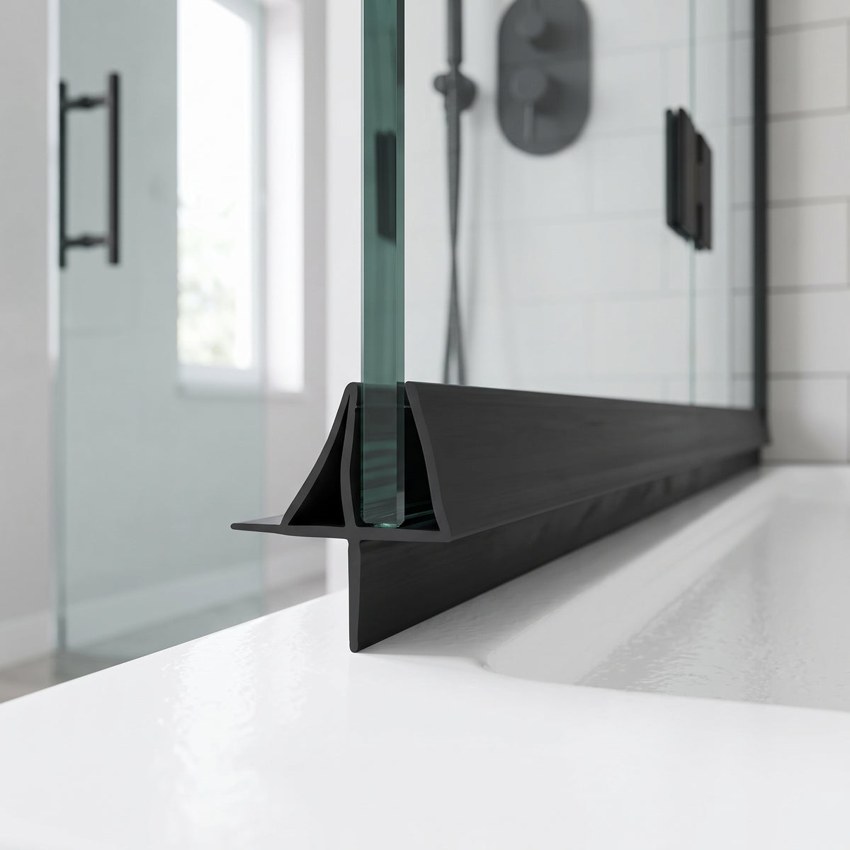 Black seal running along the foot of a glass shower panel on a white tray, black handles behind