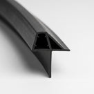 Length of black shower seal on white, glass channel with gripping nibs and a wide sloping wing