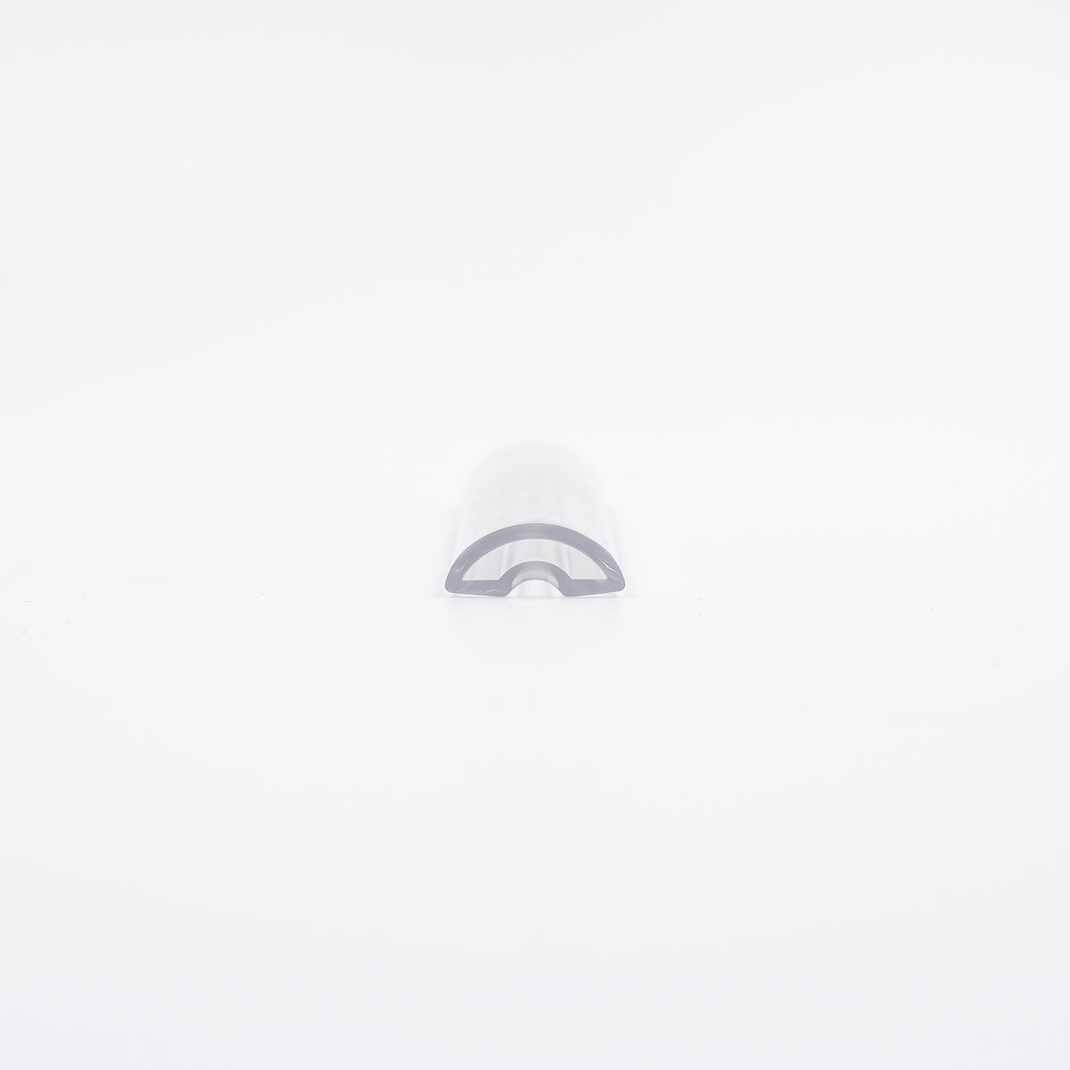 Short offcut of clear threshold seal on white, domed top with a hollow arch through the cut end