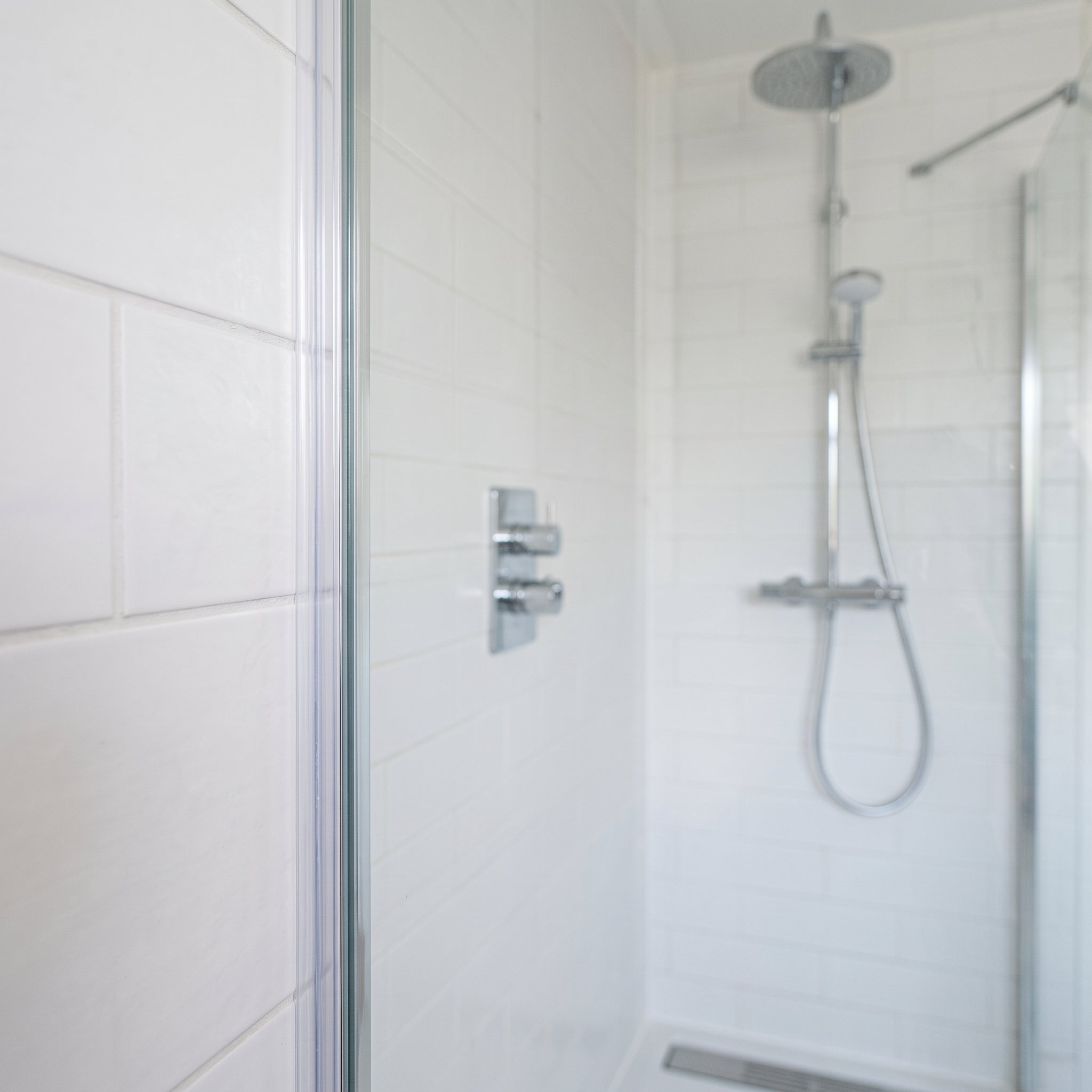 Clear SEAL120 seal on a glass panel edge - D-bubble cushion sealing the gap to the tiled wall