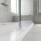 Clear seal fitted along the base of a glass bath screen, sitting on the white bath rim in a grey tiled bathroom