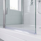 Clear seal along the bottom edge of a glass shower screen on a white tray, chrome handle behind