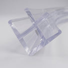 Clear PVC corner seal on white, close end-on view - cross-shaped profile with two channels meeting at 90 degrees