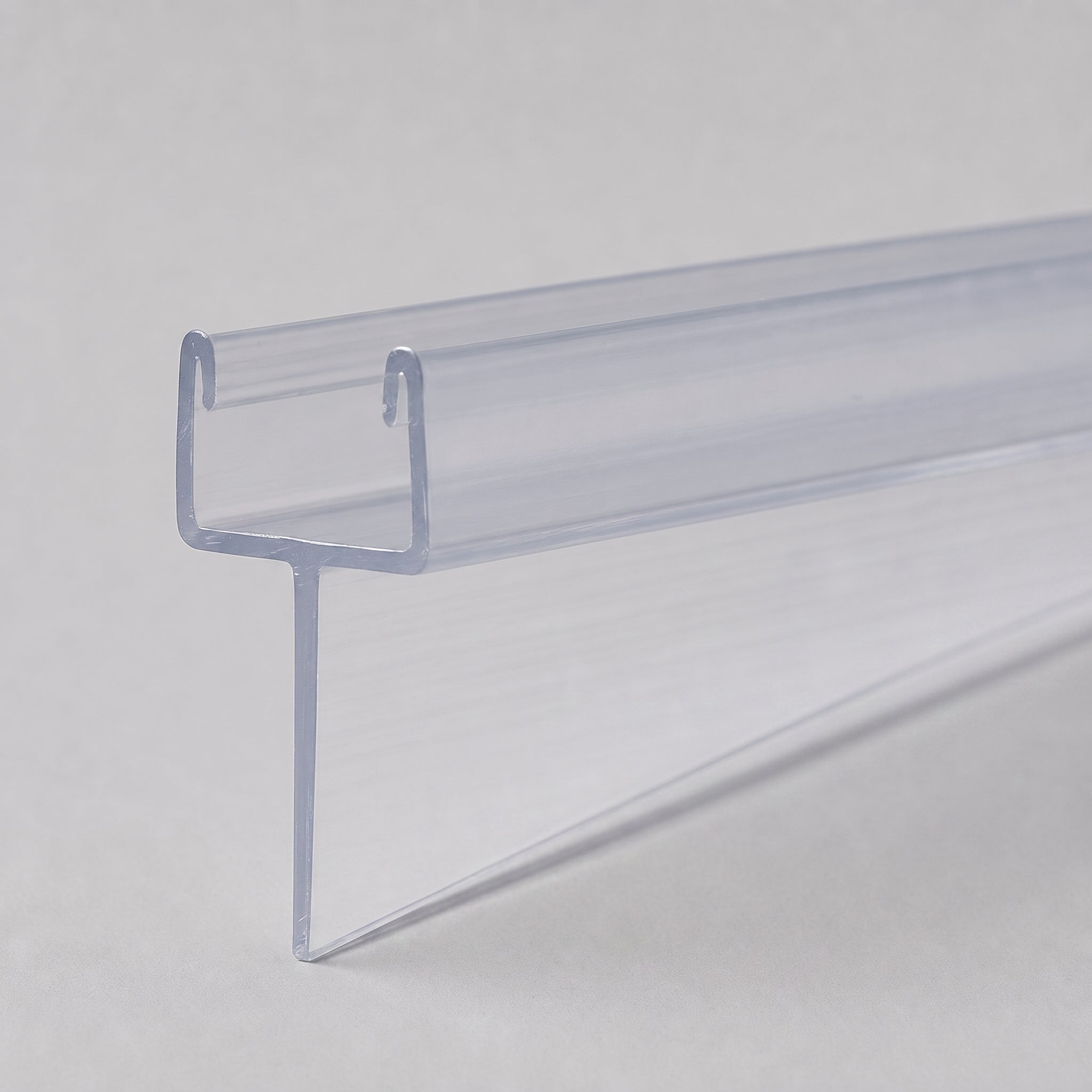 Studio shot of the tapered shower seal profile - clear PVC U-channel with fin tapering from 10mm to 2mm along its 900mm length