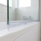 Clear tapered seal capping the bottom edge of 4-6mm glass, fin tapering from 15mm to 5mm along the bath screen