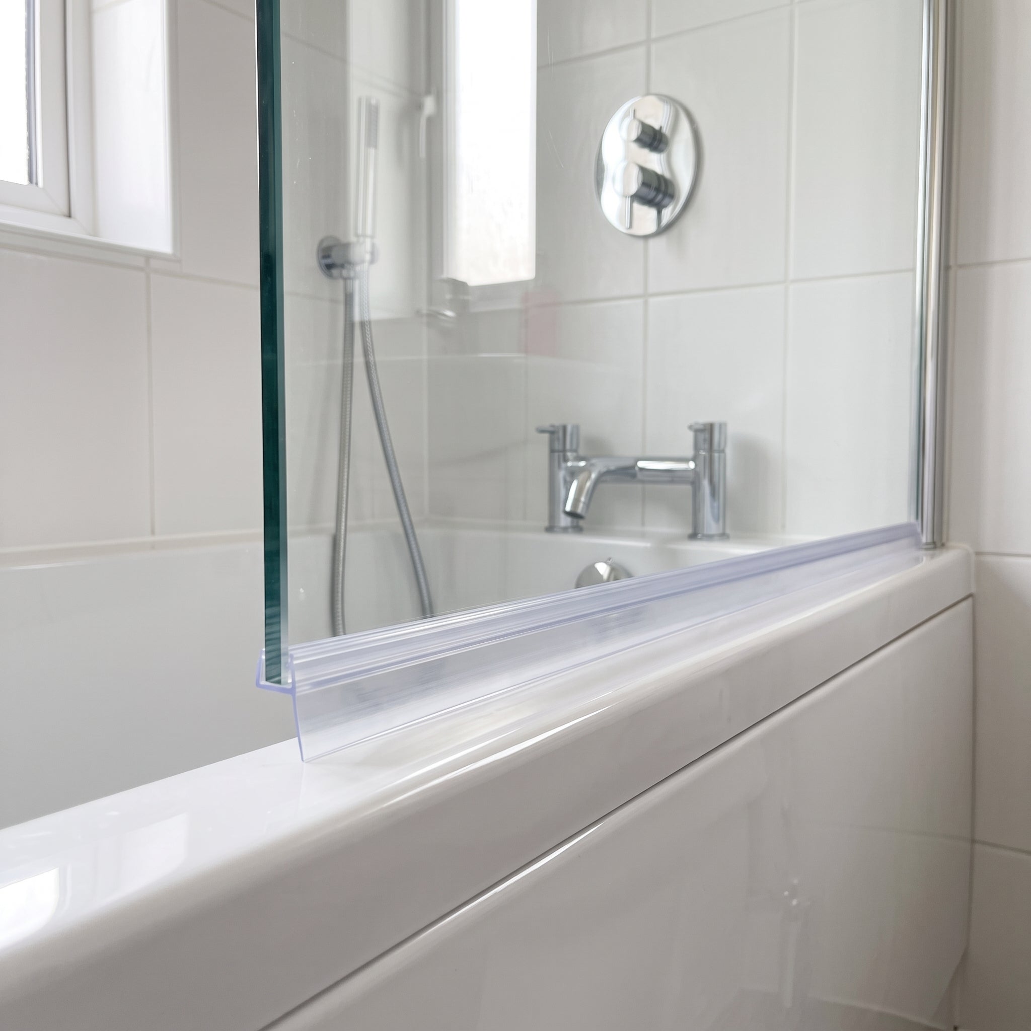 Clear SEAL171 tapered seal fitted horizontally along a bath screen bottom edge - deep fin end over the widest gap