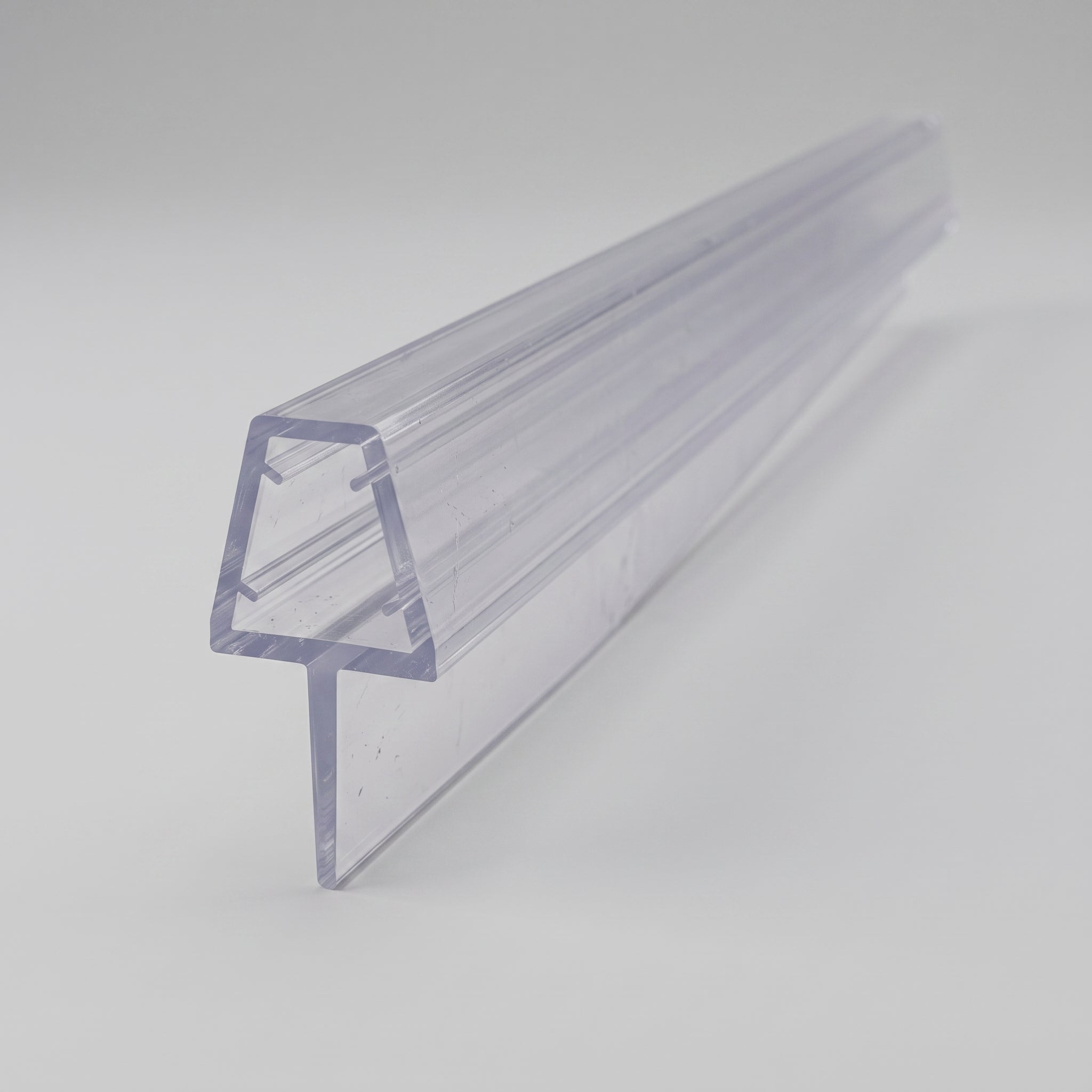 Studio shot of the tapered shower seal profile - clear PVC U-channel for 6-8mm glass with soft fin tapering from 15mm to 5mm along its 900mm length