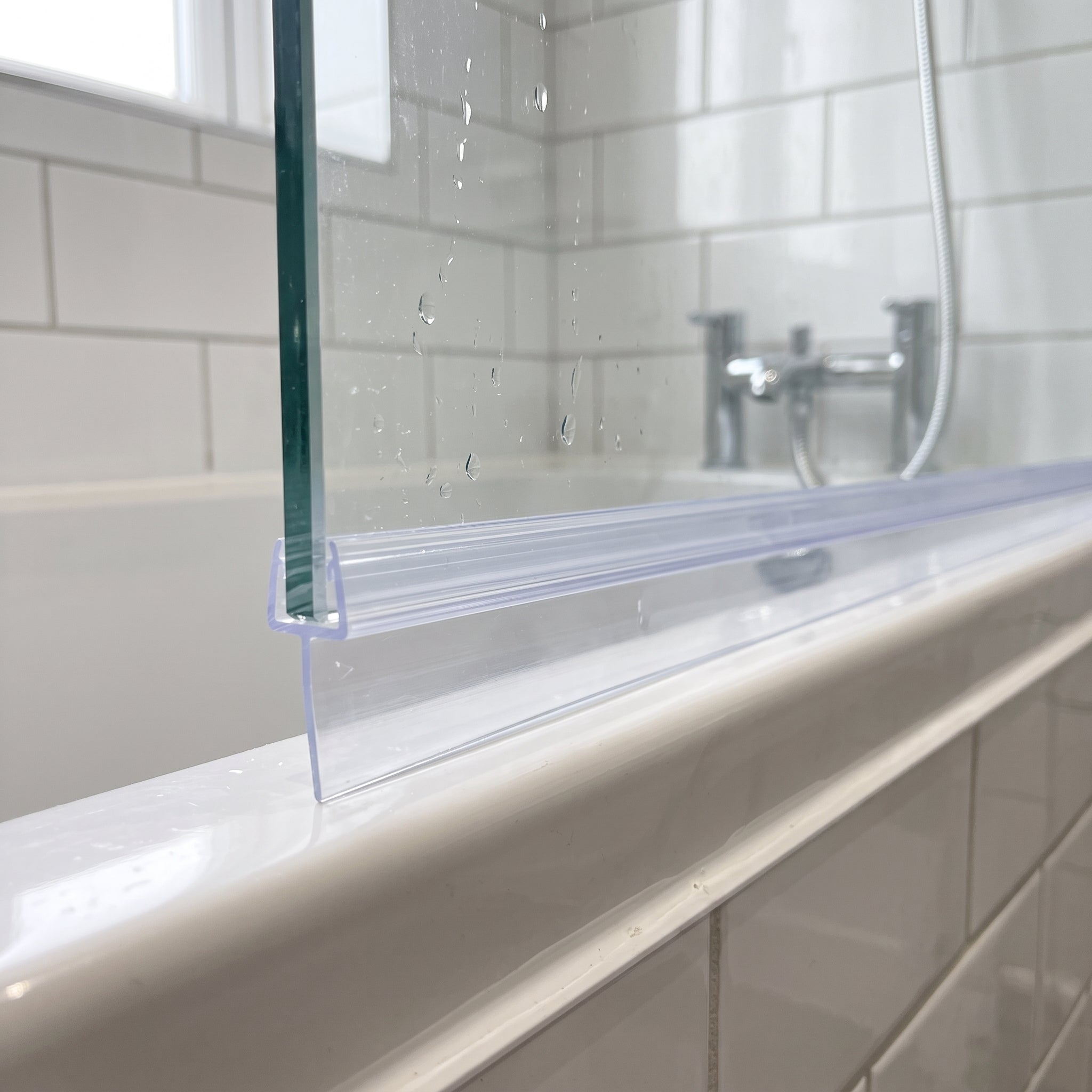 Clear tapered SEAL177 fitted horizontally on a bath screen - fin deepest over the widest gap, sealing to the bath rim