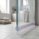 Clear tapered seal along the bottom edge of a walk-in shower screen, fin meeting a grey tiled floor