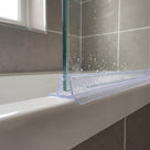 Clear seal on the bottom edge of a bath screen, flat flap and drip fin across the white bath rim