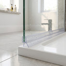 Clear seal on a green-edged glass screen over a white tray, fin spread wide, basin and window behind