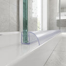 Clear seal on a green-edged glass panel, arched fin sweeping onto a white tray, sunlit grey tiles behind