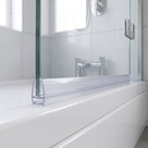 Clear seal on the bottom edge of a glass bath screen along a white bath rim, chrome taps behind