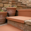 Terracotta anti-slip step paint on patio steps beside terracotta plant pots and a stone wall