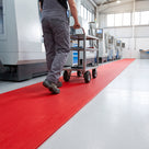 Red 14mm close-mesh PVC matting marking the trolley route past CNC machines in a clean engineering workshop